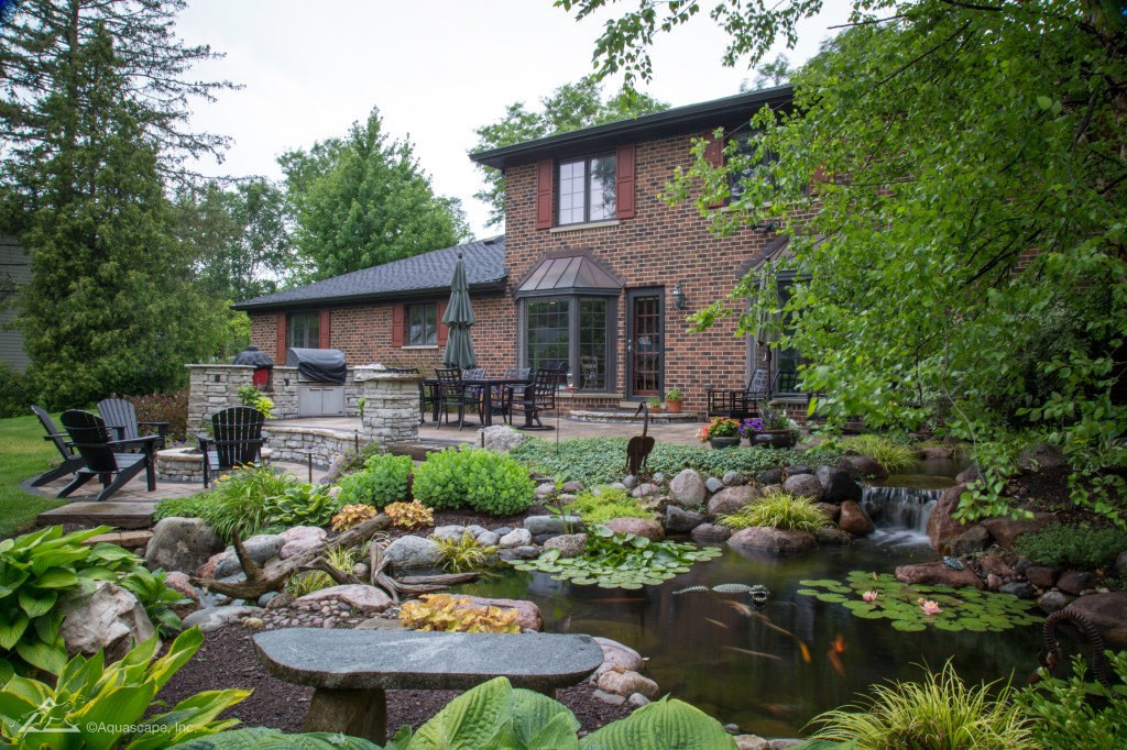large ecosystem pond with plants and stone bench